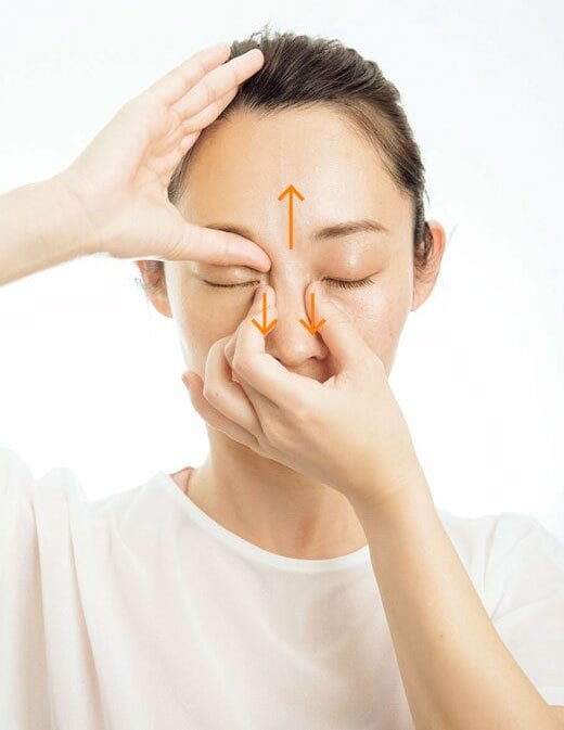 反対の手で鼻のつけ根の骨をはさみ、下に引っぱる