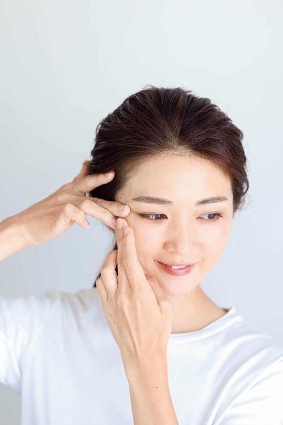 片側を両手でおさえる女性