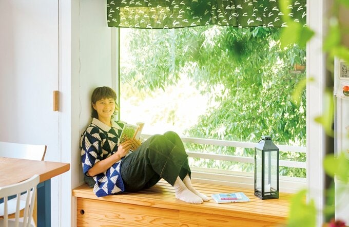 ダイニングの窓辺のベンチで読書する女性