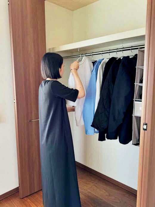 ミニマルなクローゼットに白いTシャツを収納する女性