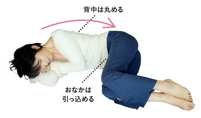 背中を丸めて寝転がりながらやせ動作をする人