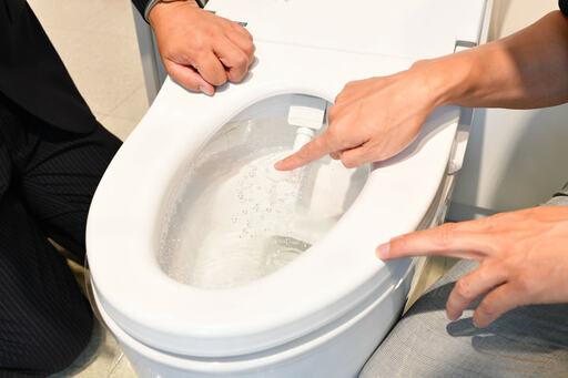 ノズルが出ている便器を指差す様子