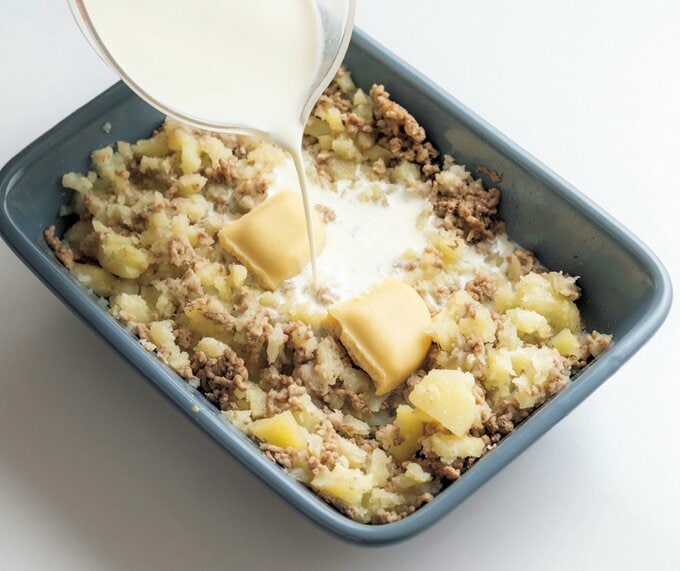 耐熱容器に入れた具材に牛乳を注いでいる写真