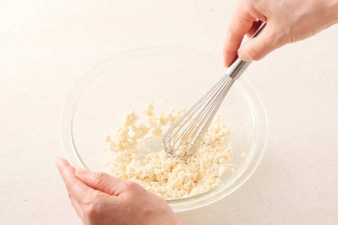 泡だて器で豆腐を混ぜている様子