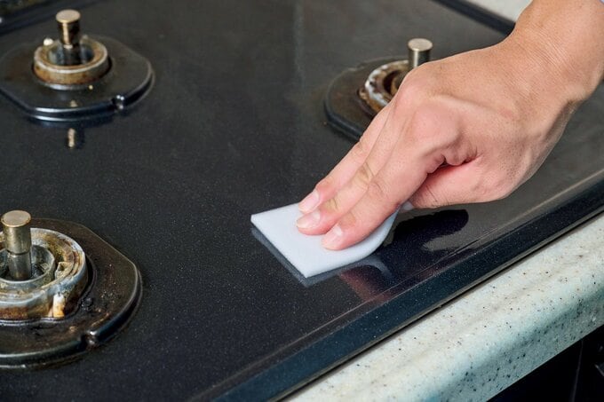 コンロ回りをメラミンスポンジで掃除する手元