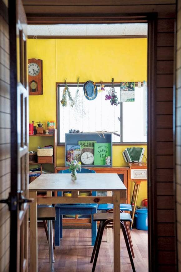 黄色の壁の部屋にテーブルとイス