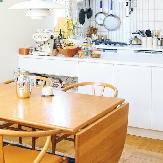 木製のダイニングテーブルと白いキッチン