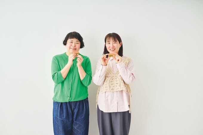 女性二人が桜と抹茶のカットバウムを両手で持ち微笑む様子