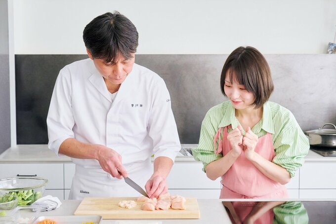 鶏肉を切る男性とのぞき込む女性