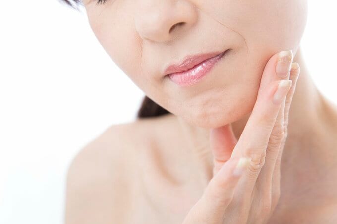 顔を片手で触っている女性のイメージ画像