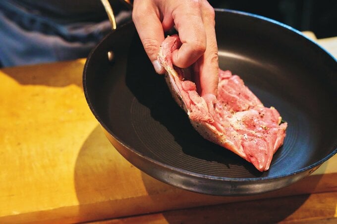 フライパンに肉を入れる様子