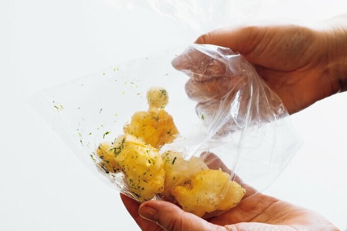 揚げたおもちをポリ袋に入れて味つけする
