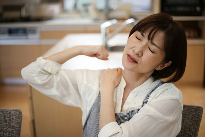 肩をおさえる女性