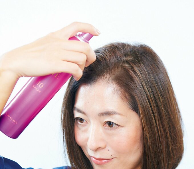 女性がヘアスプレーを髪の毛にかける様子