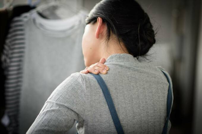 肩をおさえる女性