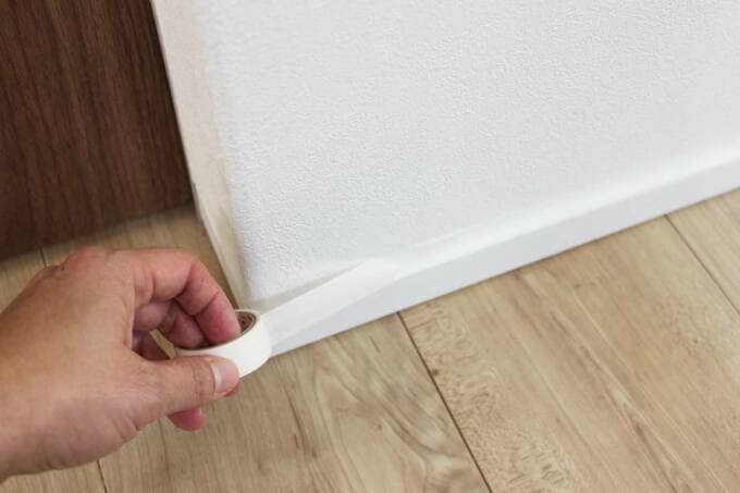 壁にテープをはる様子