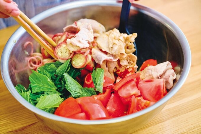 トマトと豚肉を香味ダレであえている様子