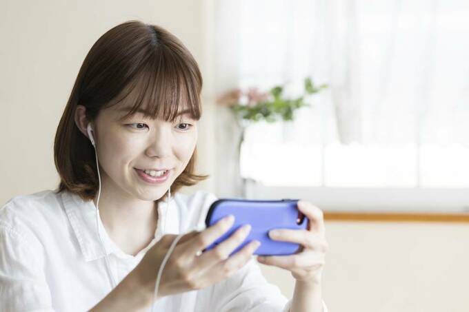 イヤホンをつけてスマホを見る女性