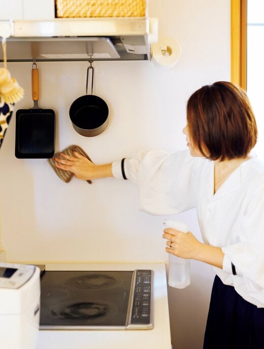 女性がキッチンの壁を拭き掃除する様子