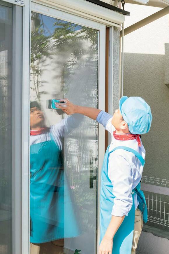 窓ガラスをスポンジでふくエプロン男性