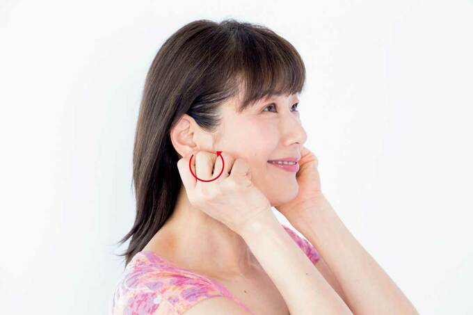耳たぶのつけ根を軽くつまみ後ろに回す様子