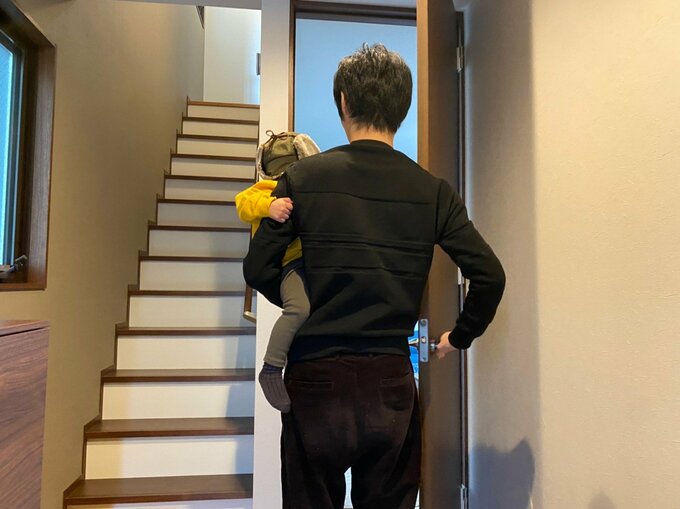 部屋のドアを開ける夫と子ども