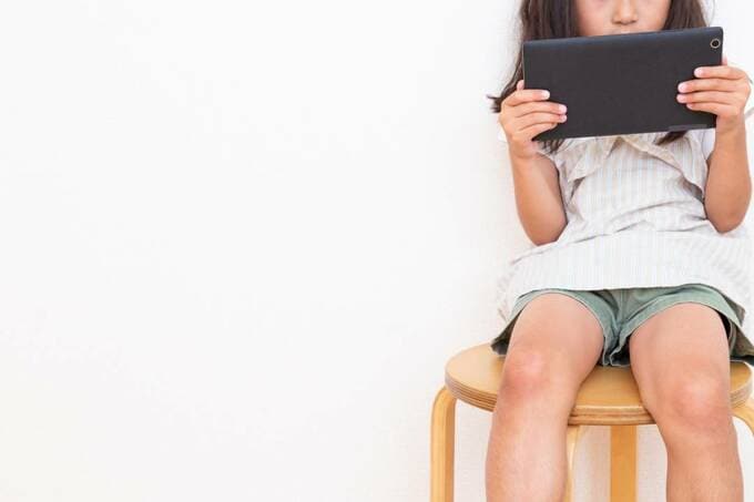 イスに座ってタブレットを持つ子ども