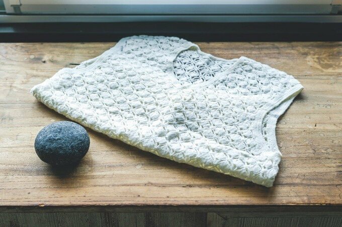 手編みの白いベストと黒い石