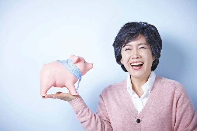 ブタの貯金箱を持つ女性