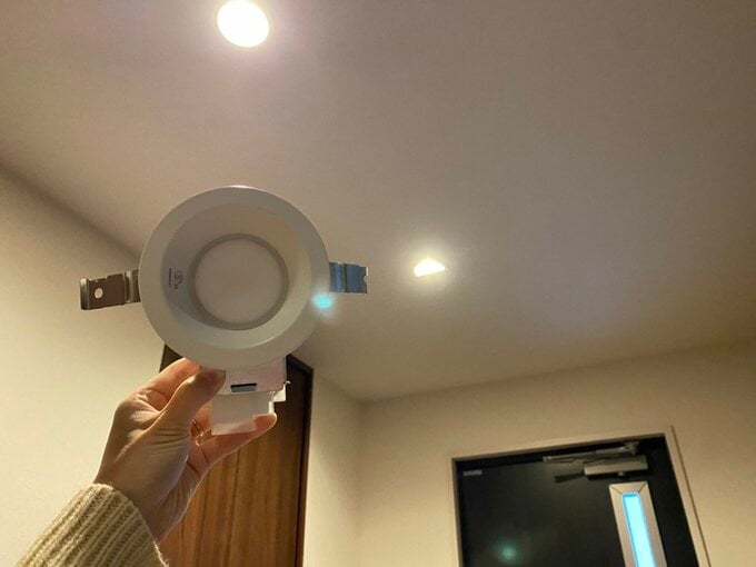 玄関ホールの取り外したダウンライトを持っている様子