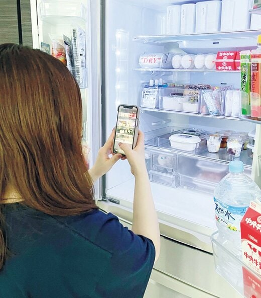 冷蔵庫内をスマホで撮影する女性