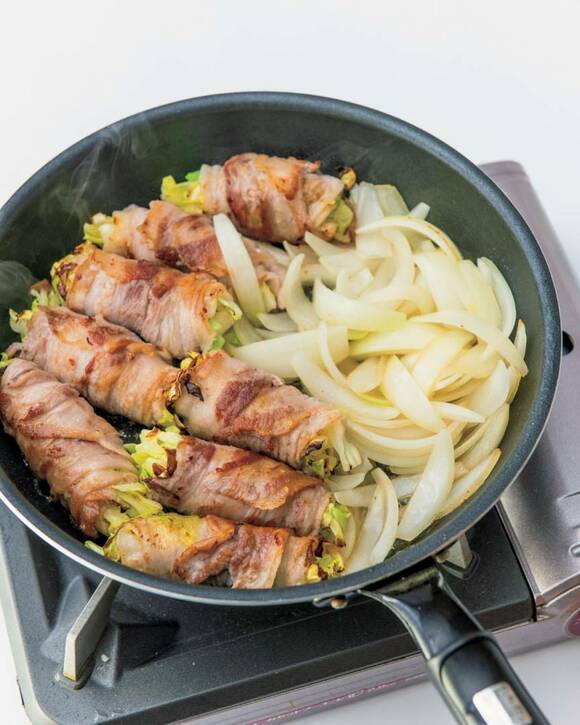 キャベツの肉巻きとタマネギをフライパンで焼く様子