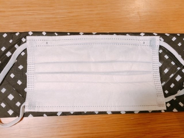 黒い柄のマスクカバーの上にマスク