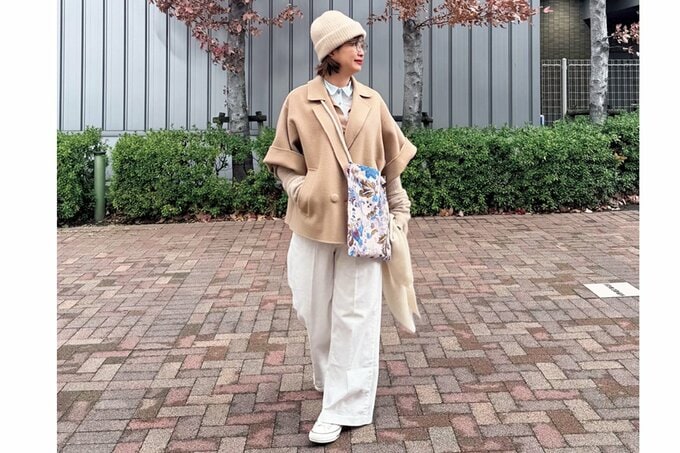 ベージュのアウターにカラフルなショルダーバッグをさげた女性