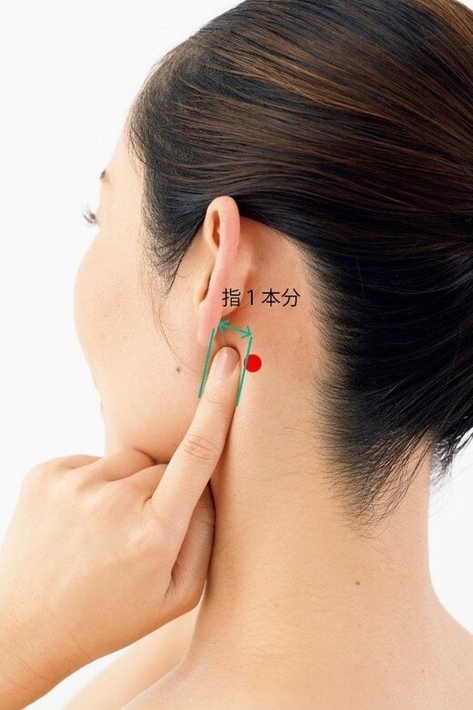 耳の後ろに指1本をあてる女性