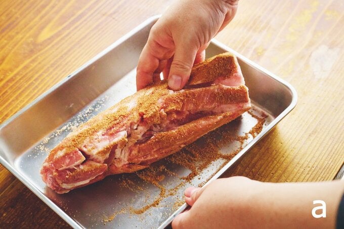 スパイスをすり込んでいる豚肉