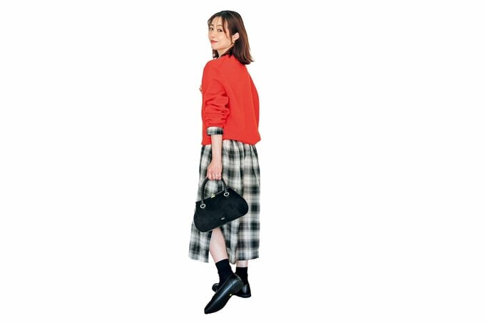 オレンジニット×チェック柄ワンピースの女性が振り向く様子