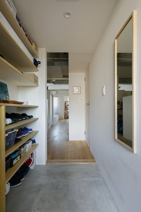 左側の壁面をオープン棚にした玄関ホール