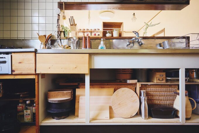 大きな茶箱や立てかけたカッティングボードが見えるシンク下