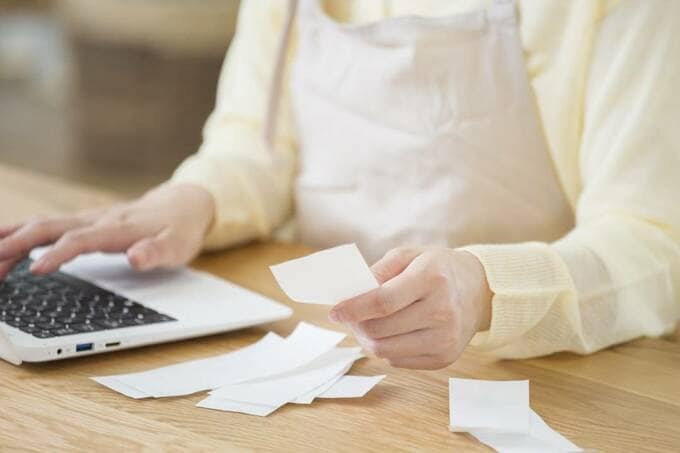 レシートを持ちながらパソコンを操作する