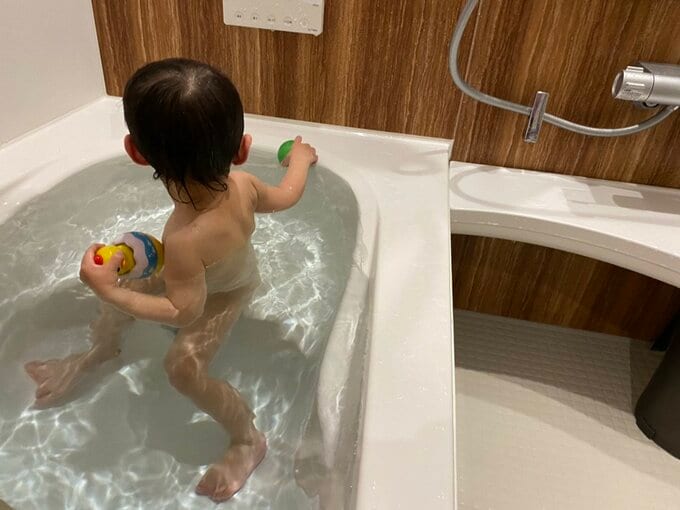 浴槽のベンチに座って遊ぶ男の子