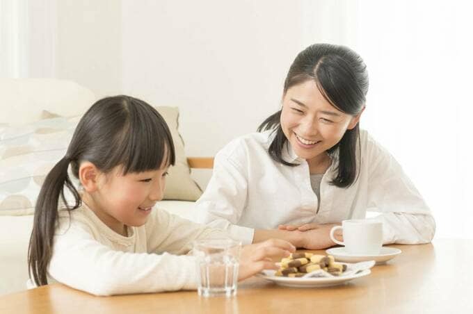 お菓子を持つ子どもを見る女性