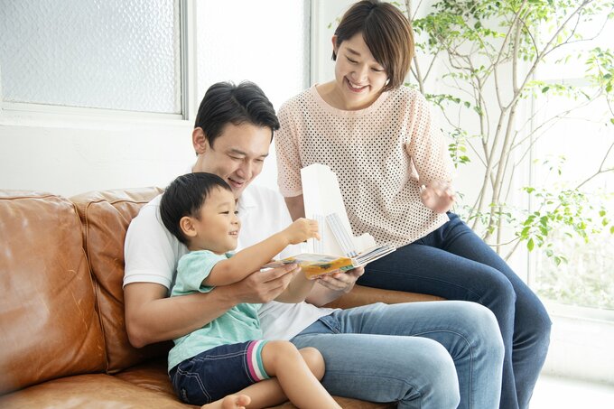 子どもに絵本の読み聞かせをする両親