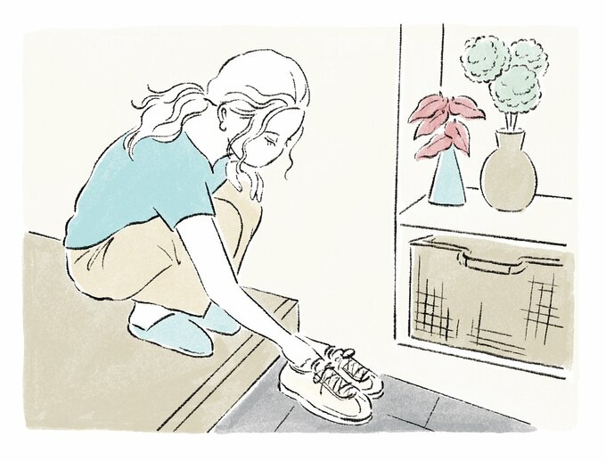 玄関でしゃがみ、靴を持つ女性のイラスト