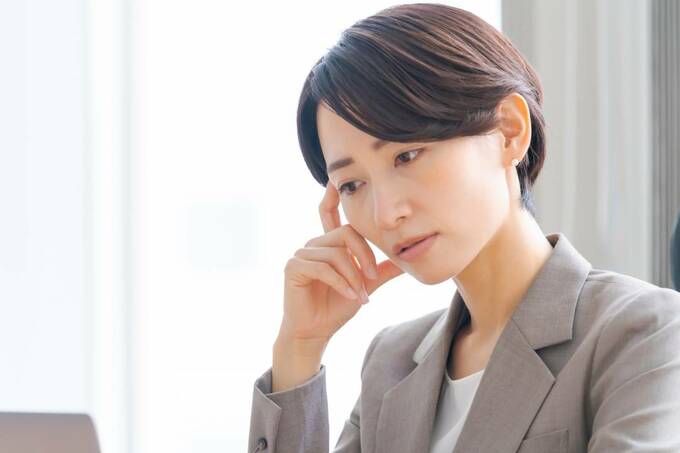 悩むスーツの女性