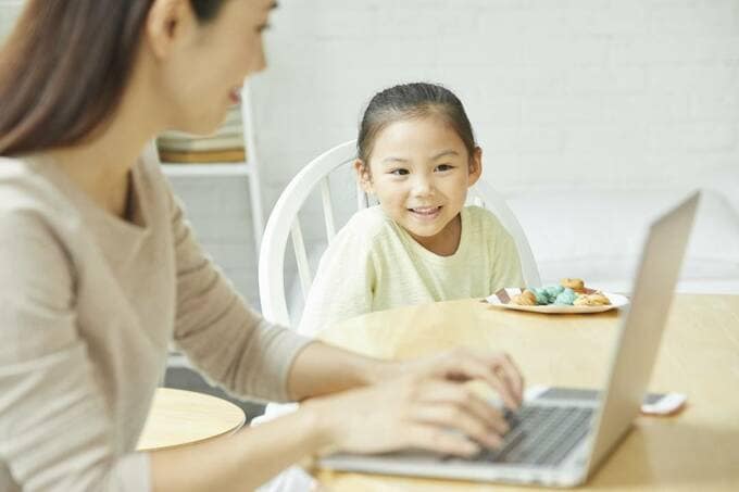 パソコンを操作する女性とそれを見ている子ども