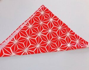 布の四方の端を始末して、三角に折ります。