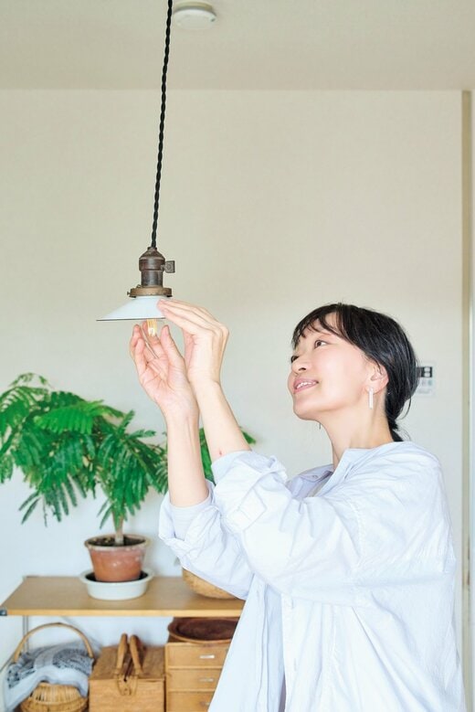 天井からつるされた照明に手を添える女性