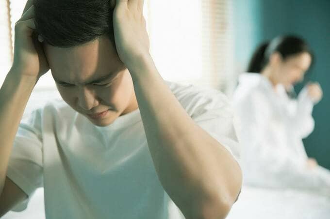 頭を抱える男性の後ろに女性