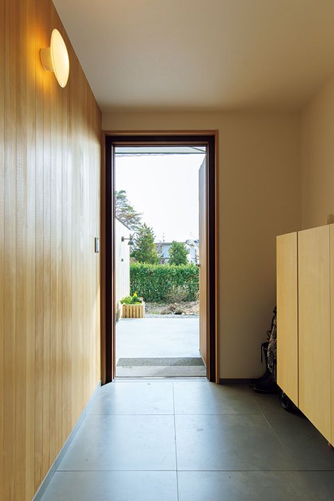 木製フェンスの延長線上にある玄関の壁は板張りに